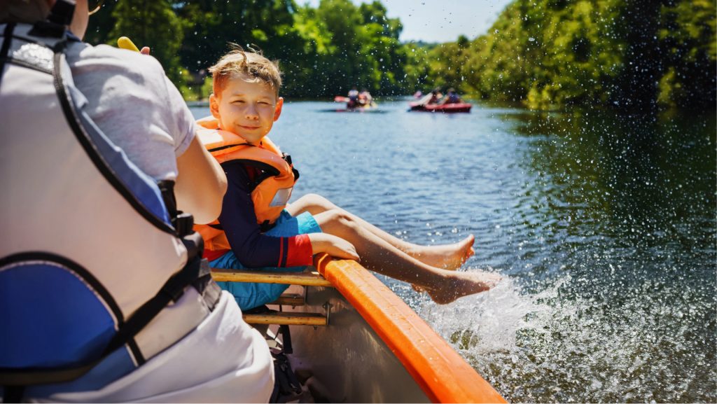 A happy child boating in summer. Splashes of water on a boat tour.